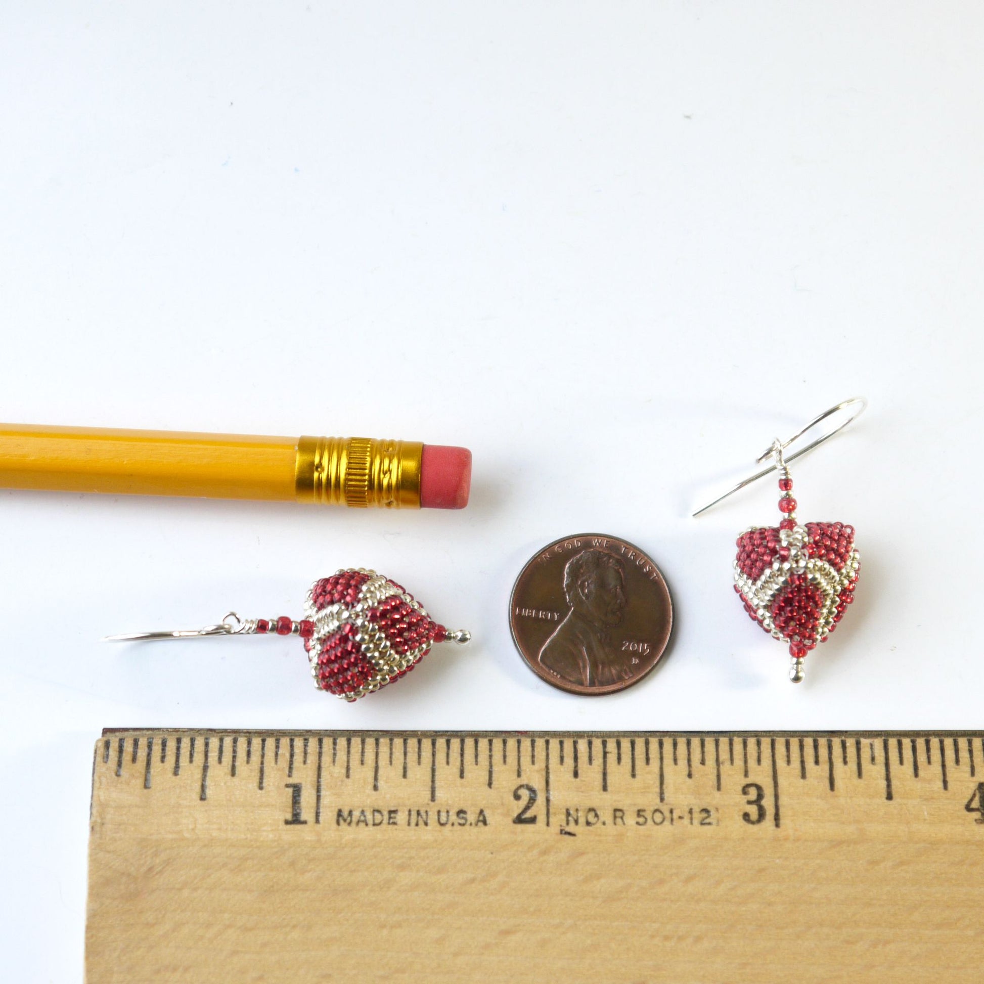 1 and 5/8 inch long triangle-shaped earrings next to a penny and a ruler on a white background