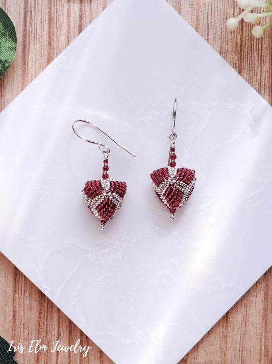 triangle-shaped beaded pomegranate red and silver seed bead earrings on a white napkin with 'Iris Elm Jewelry' branding.