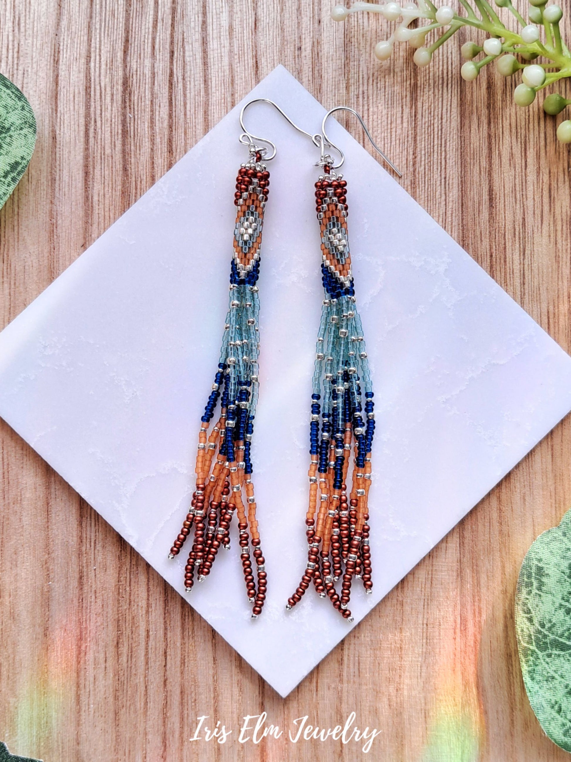 blue and orange seed bead fringe tassel earrings on white marble surface with Iris Elm Jewelry branding