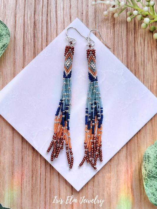 blue and orange seed bead fringe tassel earrings on white marble surface with Iris Elm Jewelry branding