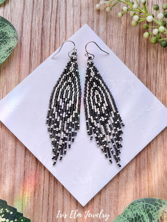 Beaded art deco grey zebra seed bead fringe earrings on a white tile with a natural background