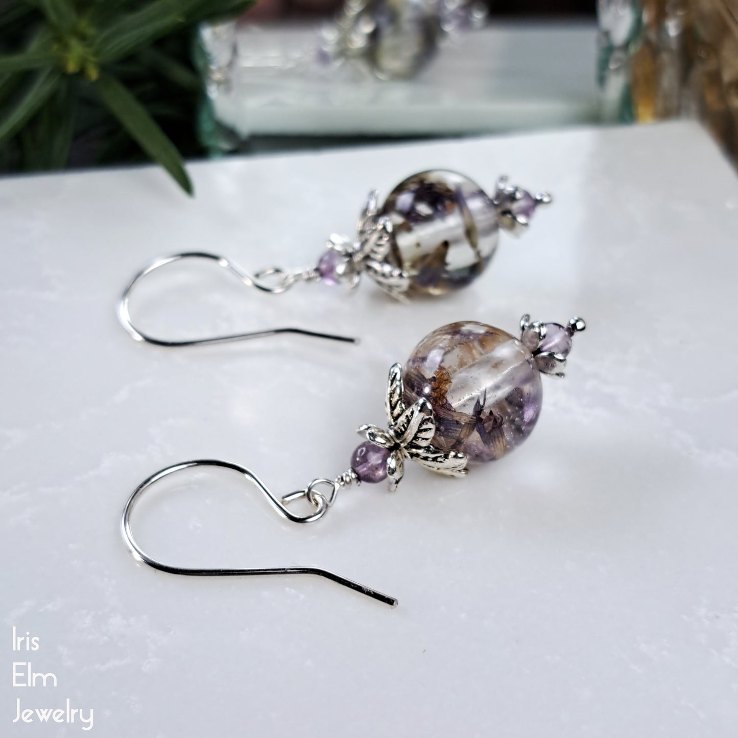 anise hyssop wildflowers in resin beaded earrings with amethyst gemstone accents on a white surface with 'Iris Elm Jewelry' branding.