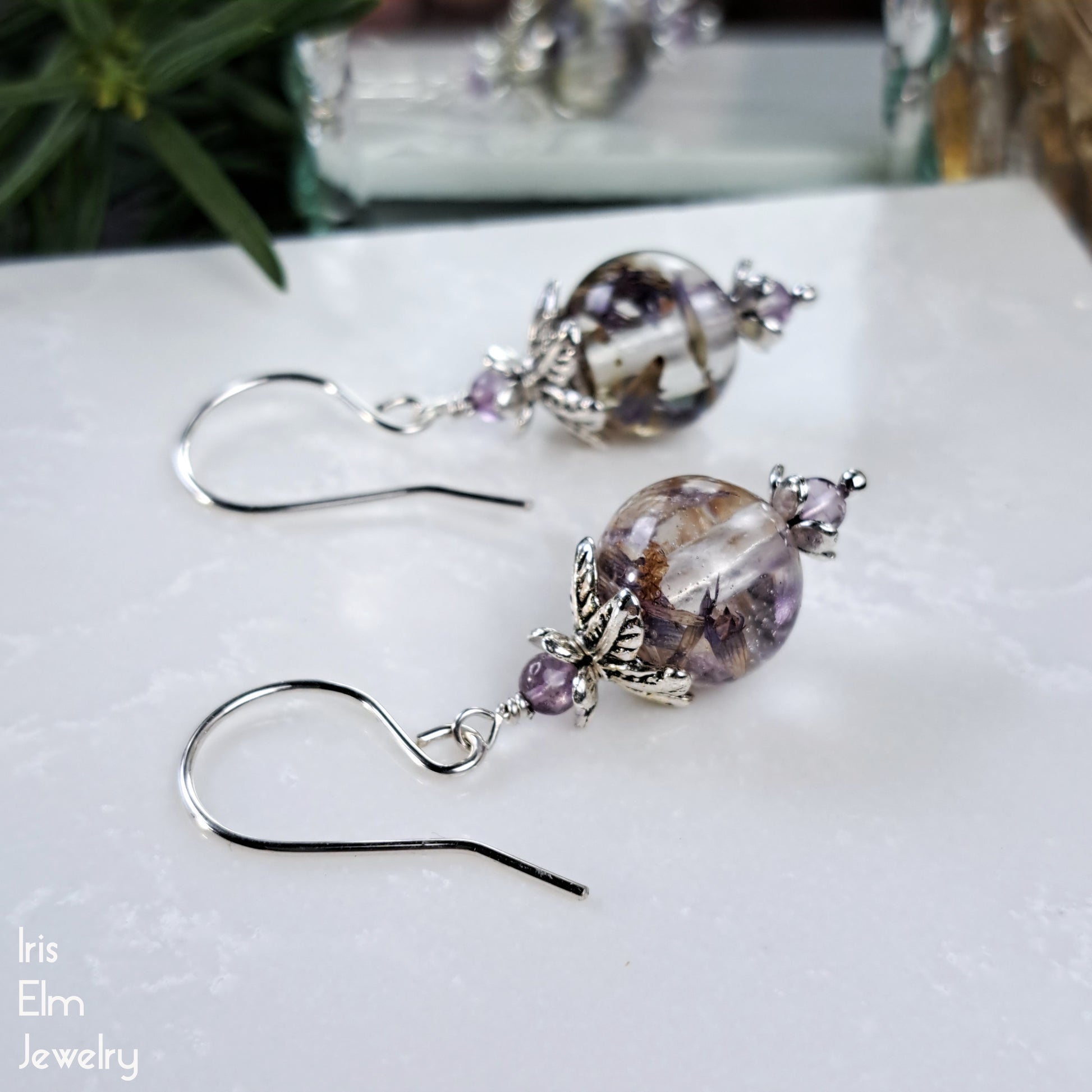 anise hyssop wildflowers in resin beaded earrings with amethyst gemstone accents on a white surface with 'Iris Elm Jewelry' branding.