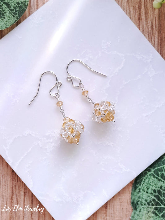 Pair of sterling silver earrings with yellow citrine gemstone beads on a white cloth