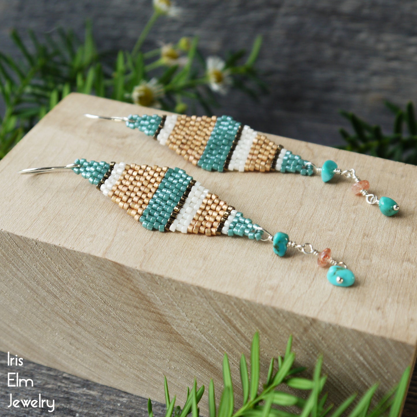 Beaded sterling silver kite shaped seed bead earrings with turquoise chips and sunstone on a wooden block with natural background