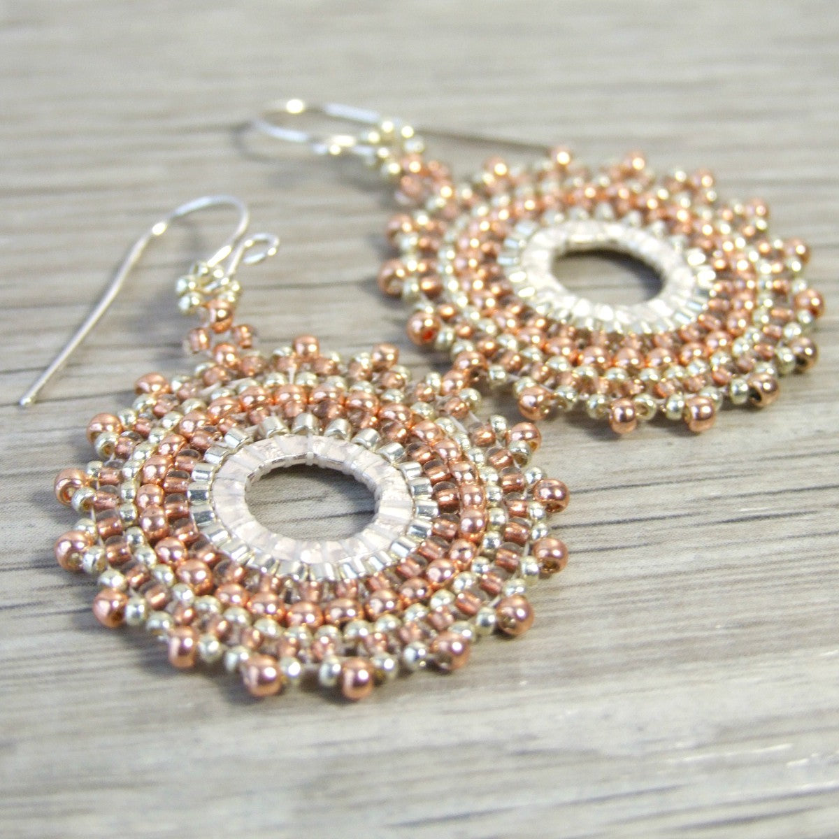 Glass woven seed bead hoop earrings on a wooden surface