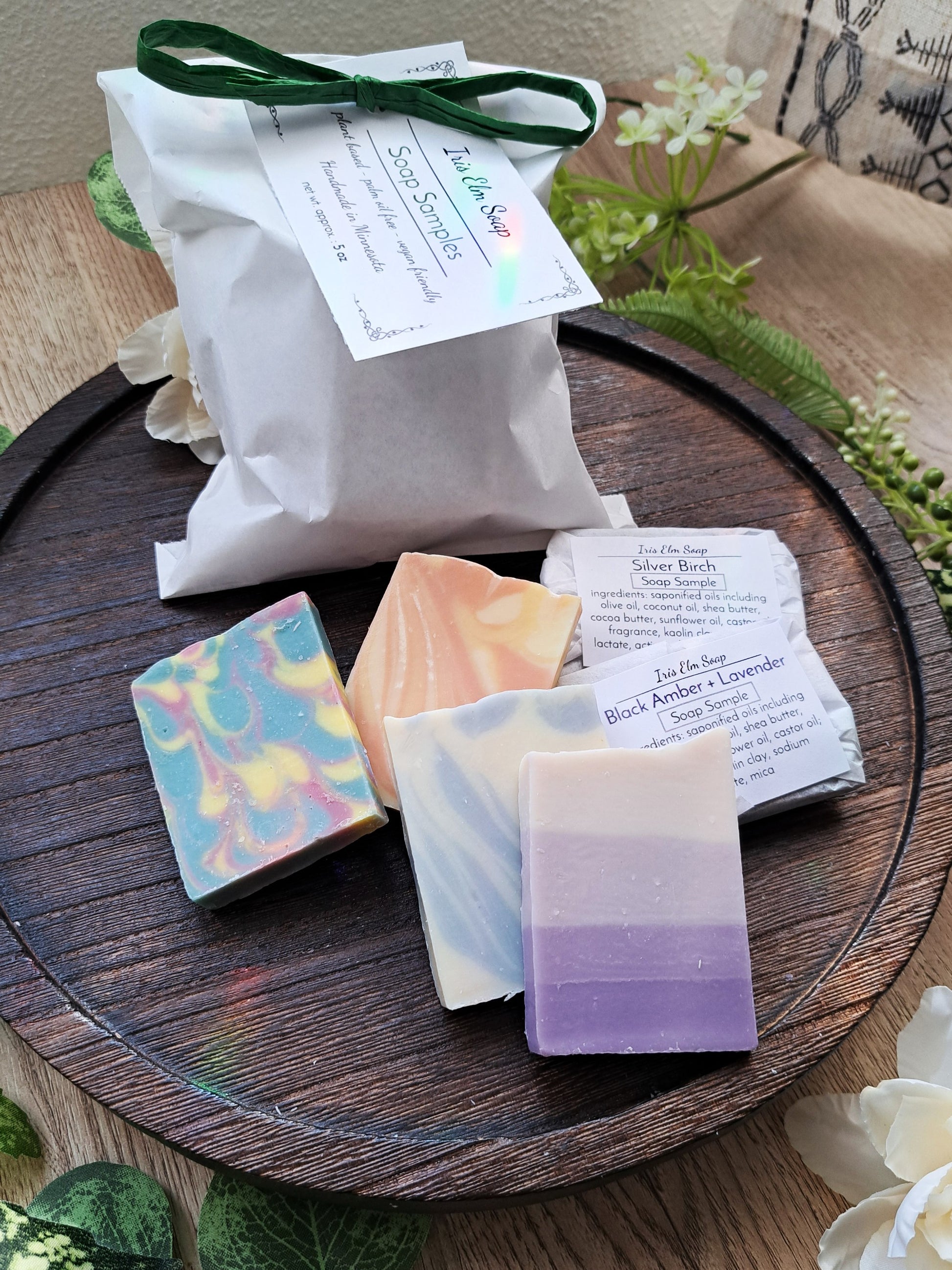 Handmade soap bars sample gift pack on a wooden tray with labels and packaging.