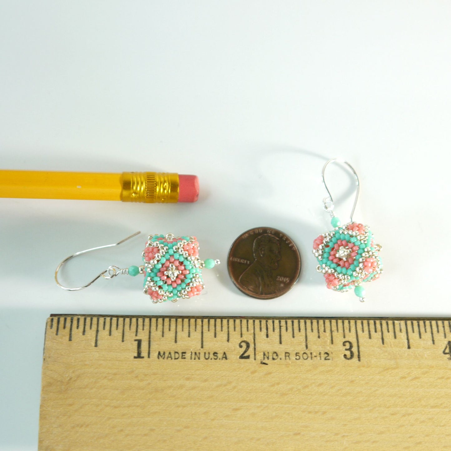 Pair of 1 and 7/8 inches long beaded cube earrings next to a pencil and penny on a white background