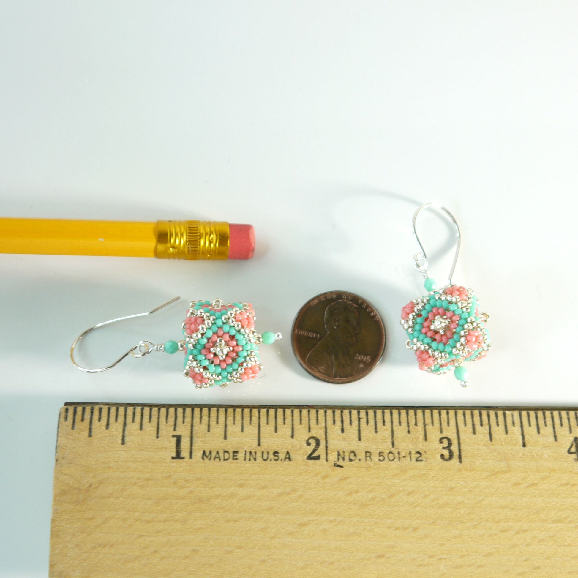 Pair of 1 and 7/8 inches long beaded cube earrings next to a pencil and penny on a white background