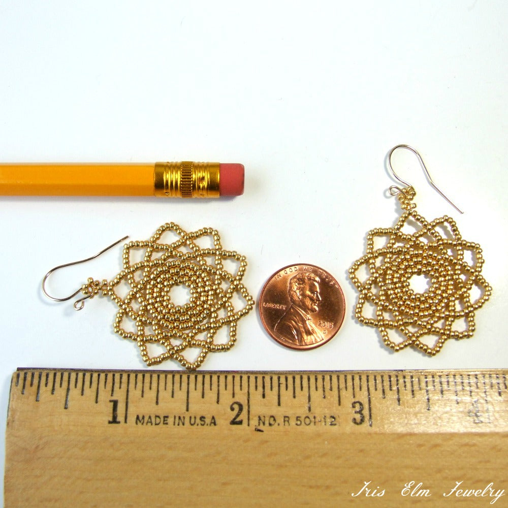 Gold mandala earrings next to a penny and pencil on a white background, with 'Iris Elm Jewelry' branding.