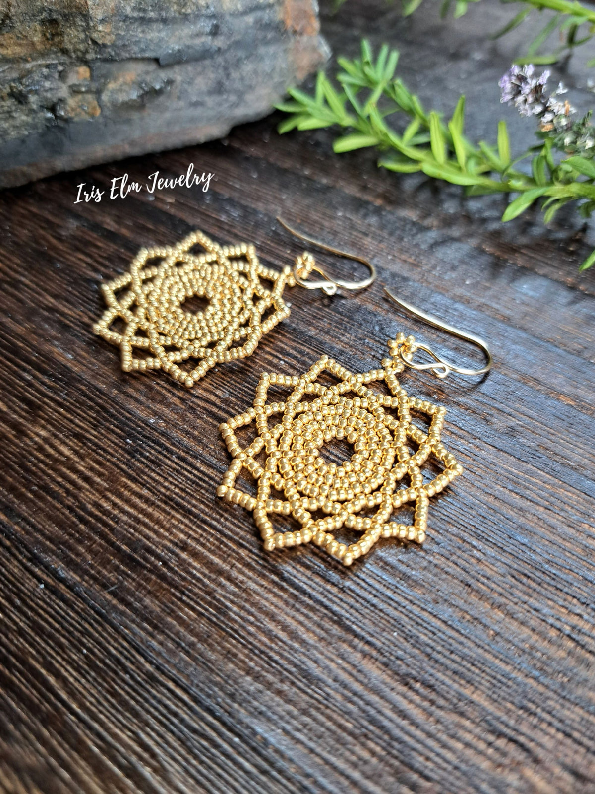 gold seed bead woven mandala handmade earrings by Iris Elm Jewelry on wooden surface