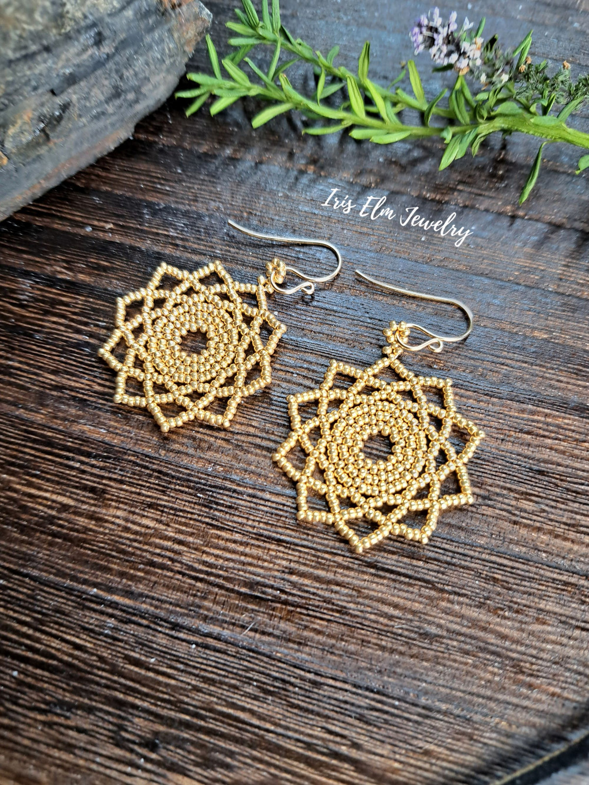 gold seed bead woven mandala handmade earrings by Iris Elm Jewelry on wooden surface