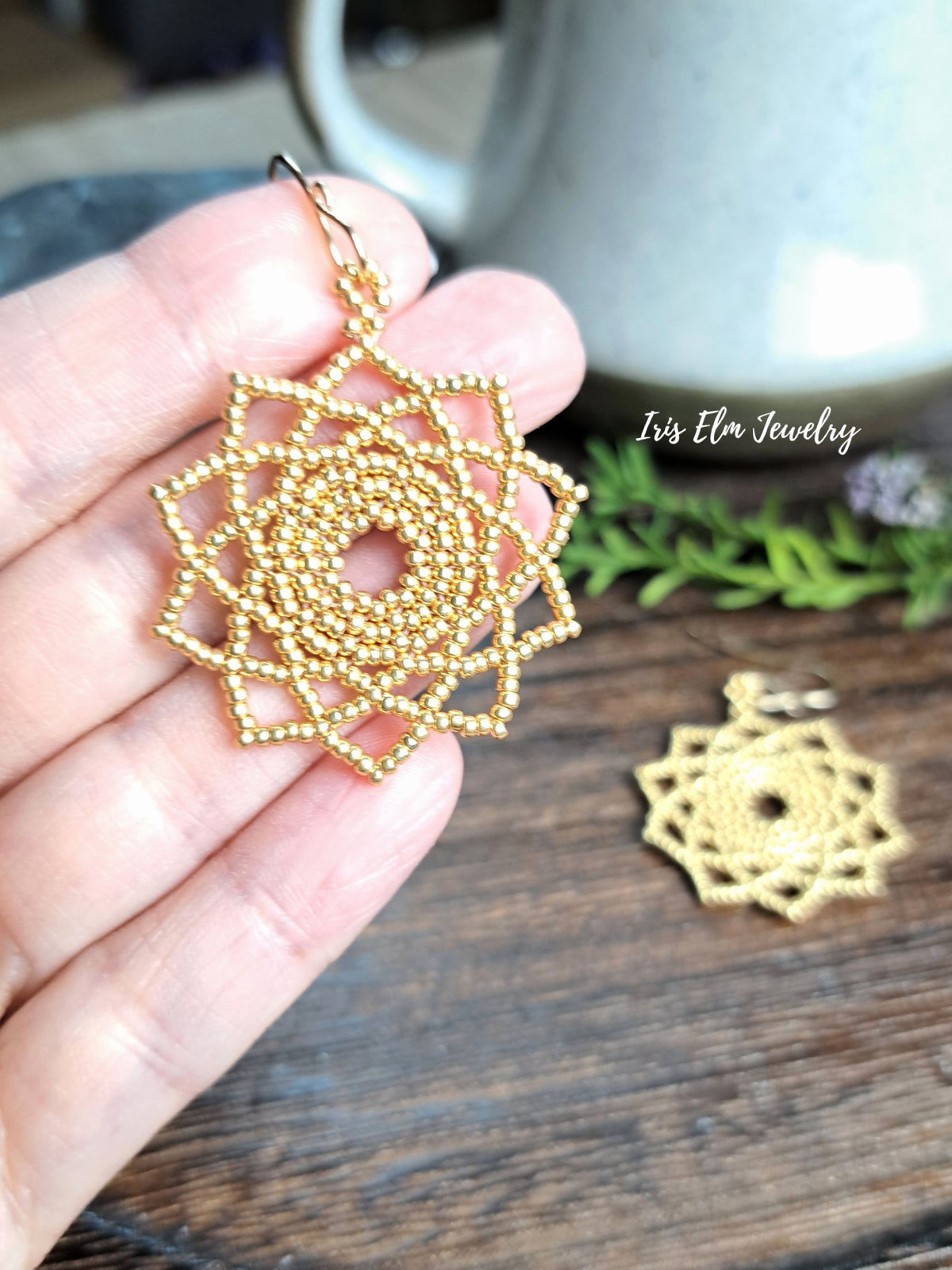 hand holding a gold glass seed bead handwoven mandala earring