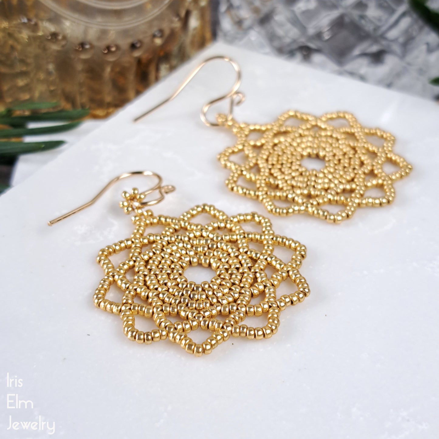 Gold beaded mandala handmade earrings on a white surface with 'Iris Elm Jewelry' branding.