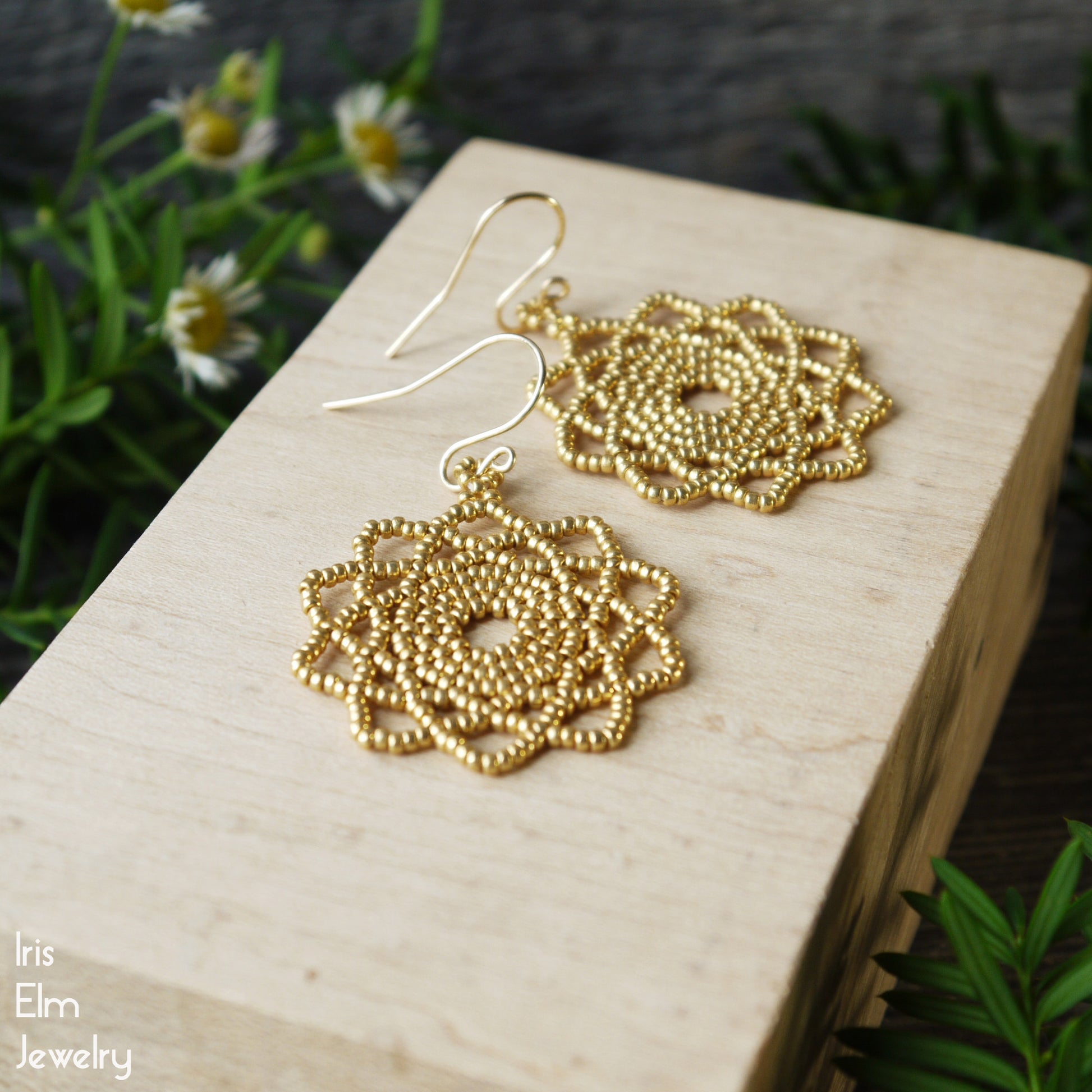 Handmade Gold circular seed bead earrings on a wooden block with a natural background