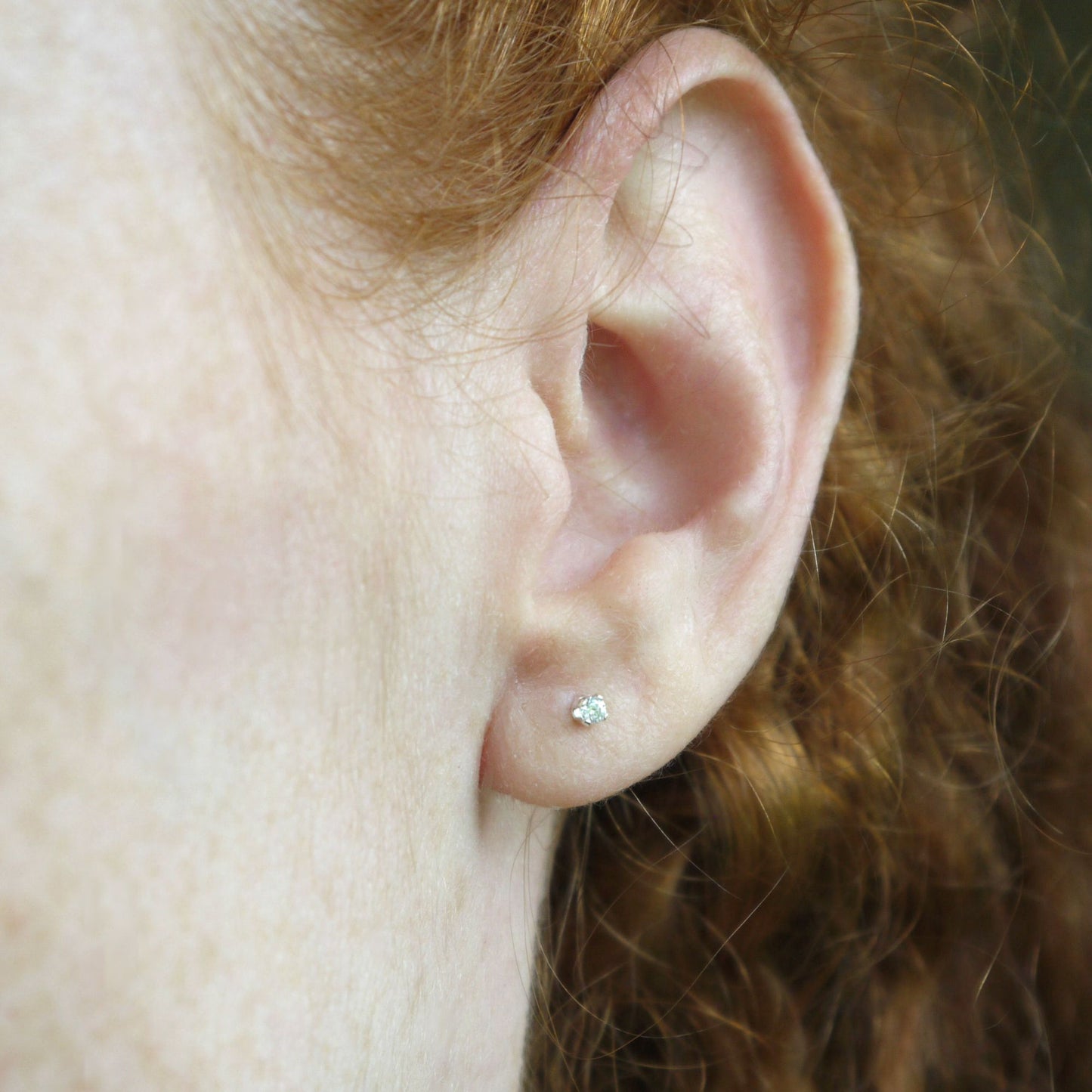 Close-up of an ear with a 2mm clear cubic zirconia stud earring