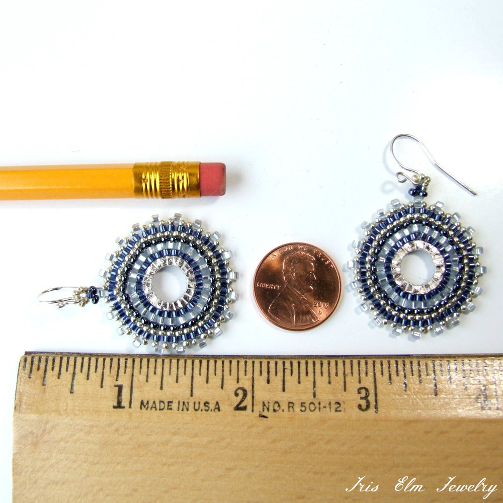Pair of beaded blue and silver circular glass bead earrings next to a penny and pencil for scale, with 'Iris Elm Jewelry' branding.