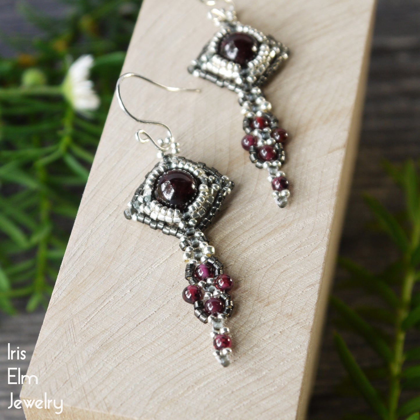 Silver and red beaded handcrafted jewelry set on a wooden surface with a natural background