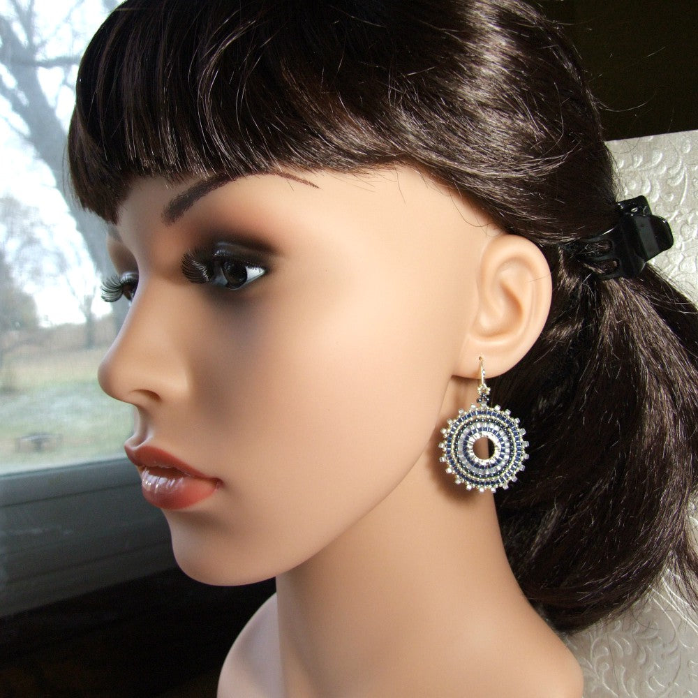 Mannequin head with dark hair styled in a ponytail and wearing a decorative blue seed bead hoop earring.
