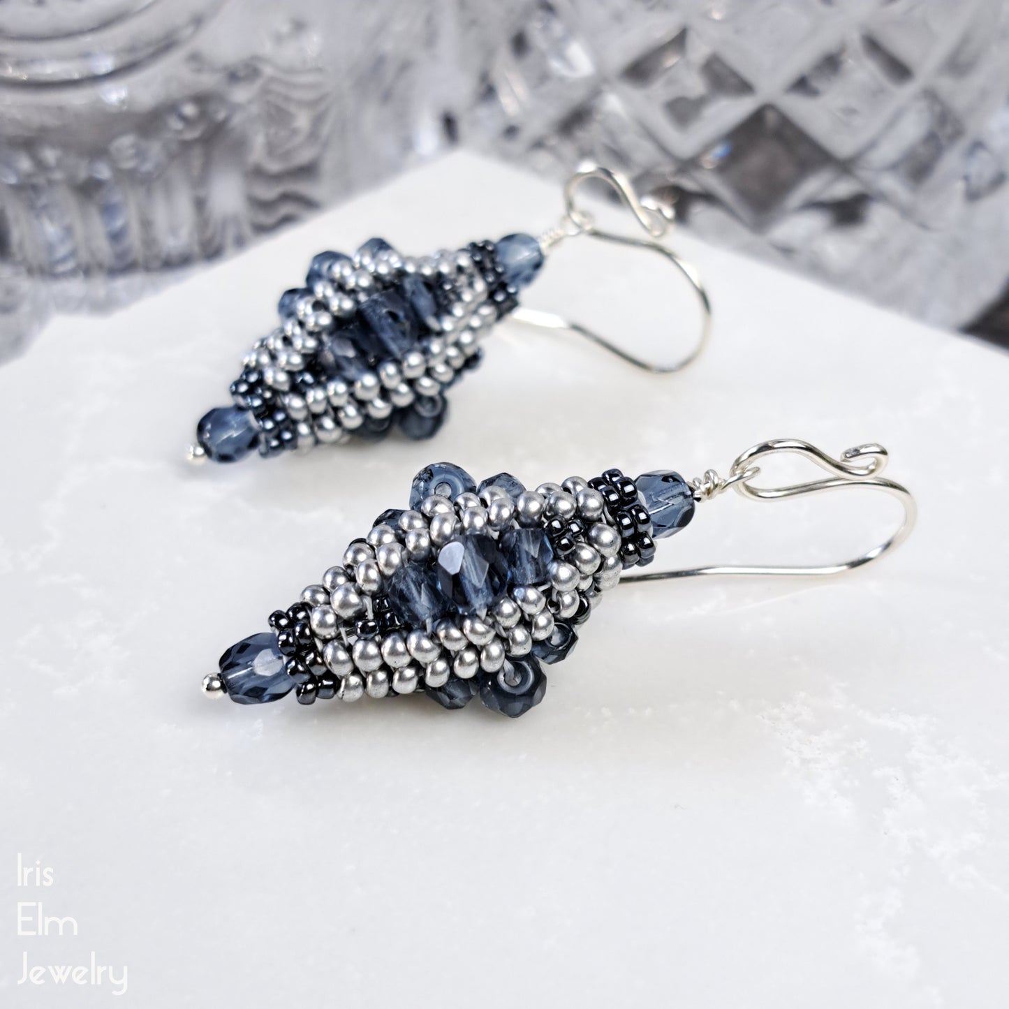 Beaded blue Czech glass lantern earrings on a white surface with a blurred background