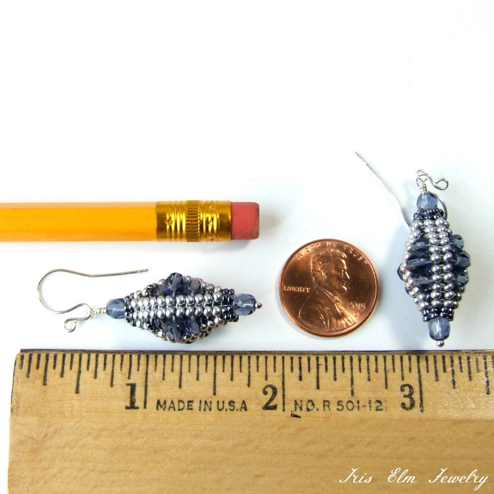 Pair of blue and silver beaded glass earrings next to a penny and ruler for scale on a white background.