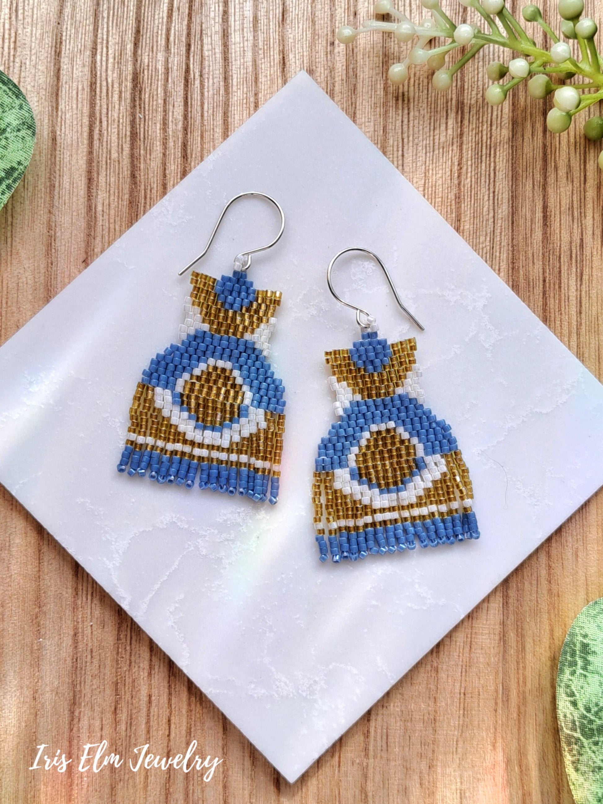 Blue and yellow modern fringe beaded earrings on a white napkin with 'Iris Elm Jewelry' branding.