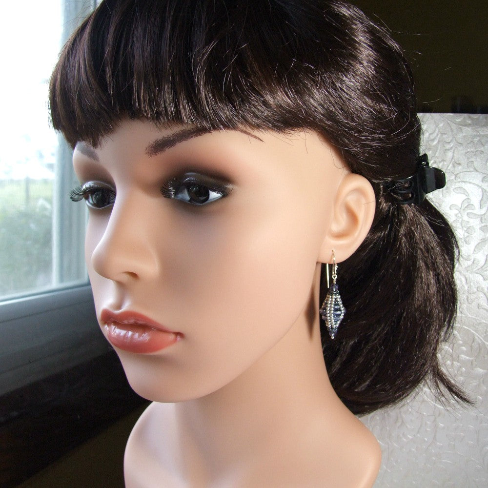 Mannequin head with dark hair styled in a ponytail and wearing blue czech glass earrings.