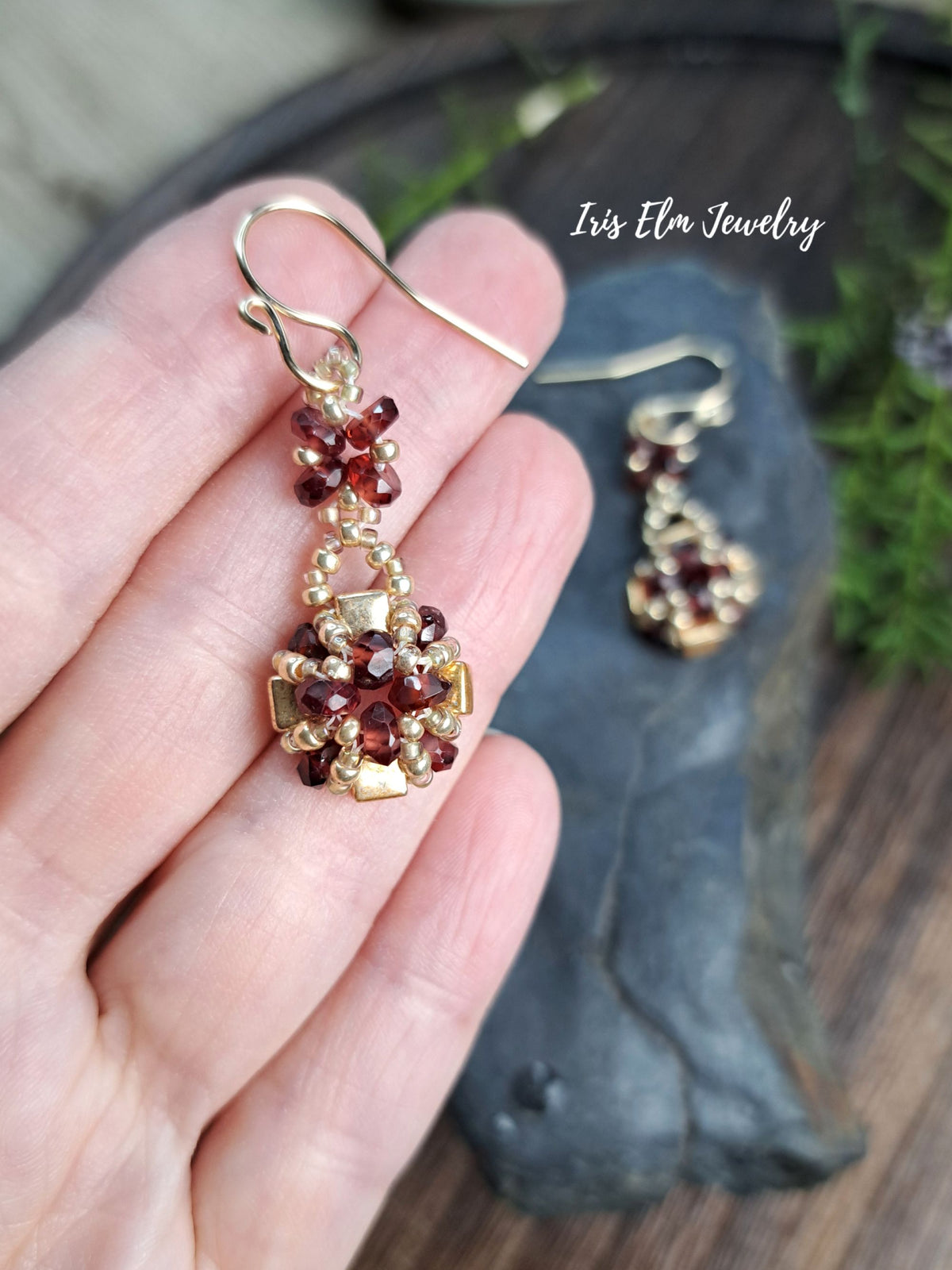 hand holding a beaded gold glass and garnet gemstone earrings by Iris Elm Jewelry