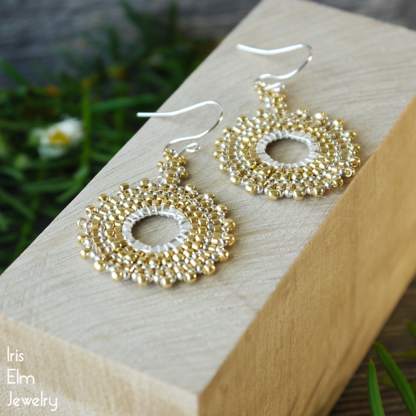 handmade Gold and silver beaded woven glass bead hoop earrings with sterling silver earwires on a wooden block with a natural background