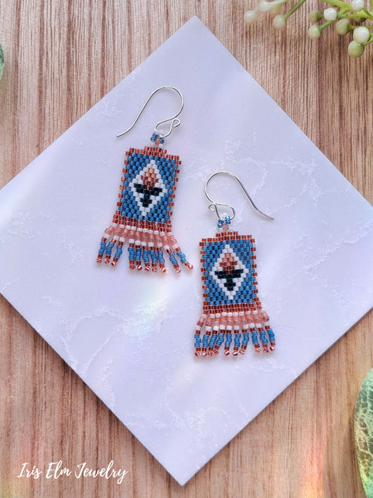 Colorful beaded blue and peach small tulip flower seed bead fringe earrings on a white napkin with 'Iris Elm Jewelry' branding