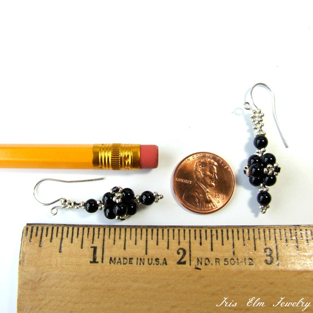 Black onyx gemstone beaded earrings with a penny and pencil for scale on a white background
