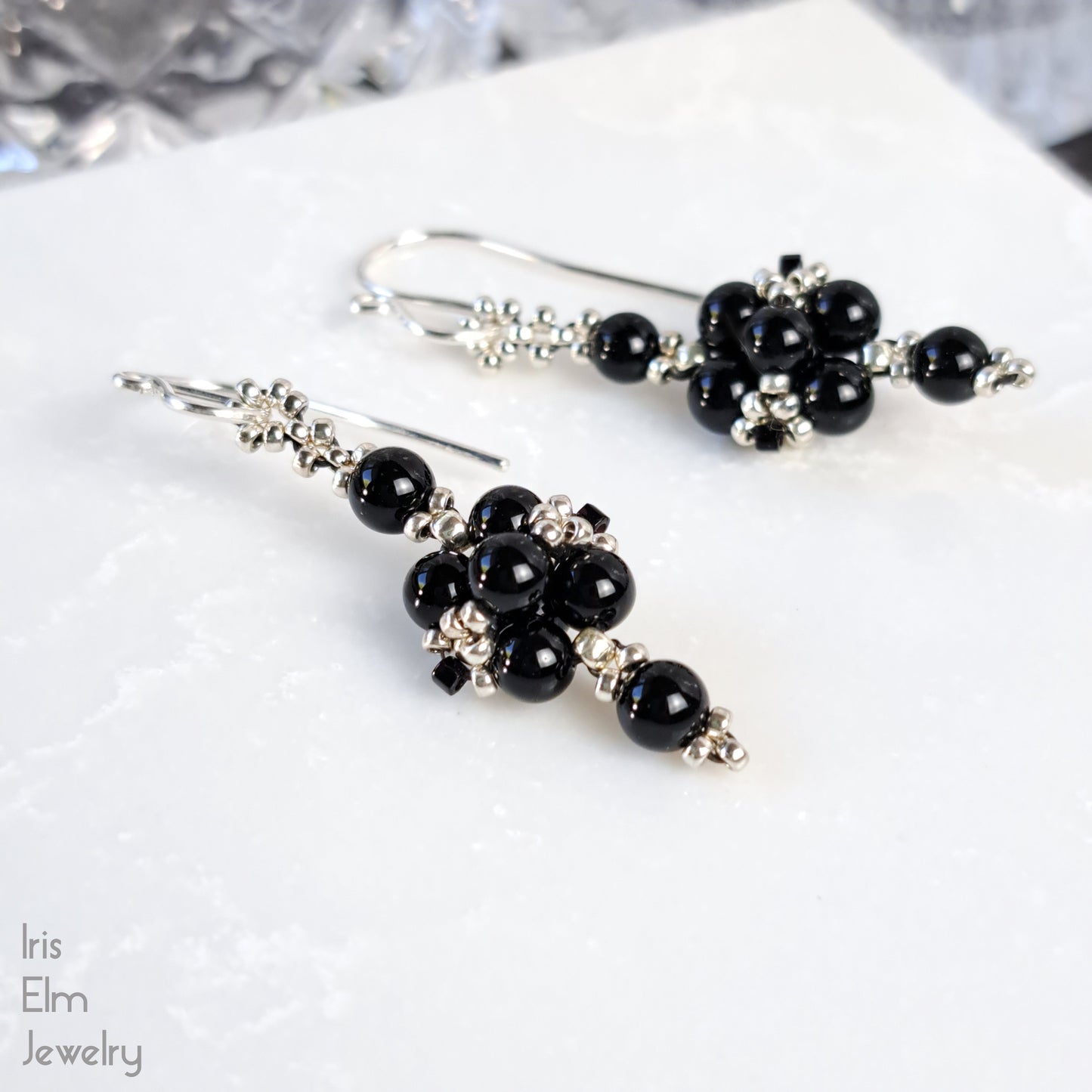 Black onyx gemstone beaded earrings on a white surface with 'Iris Elm Jewelry' branding.