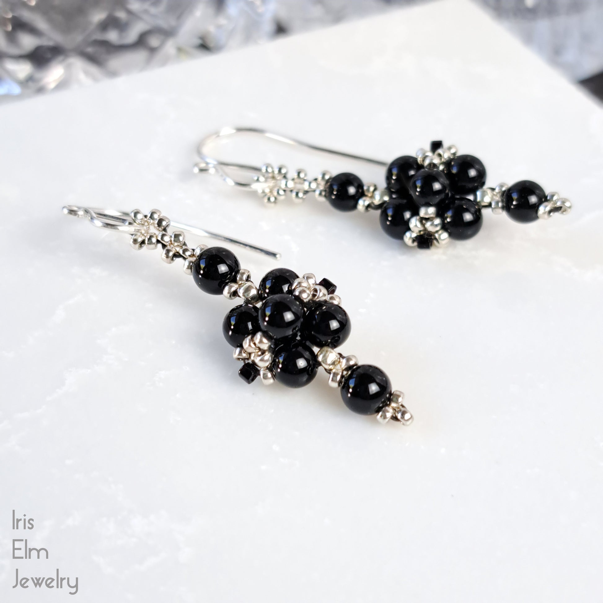 Black onyx gemstone beaded earrings on a white surface with 'Iris Elm Jewelry' branding.