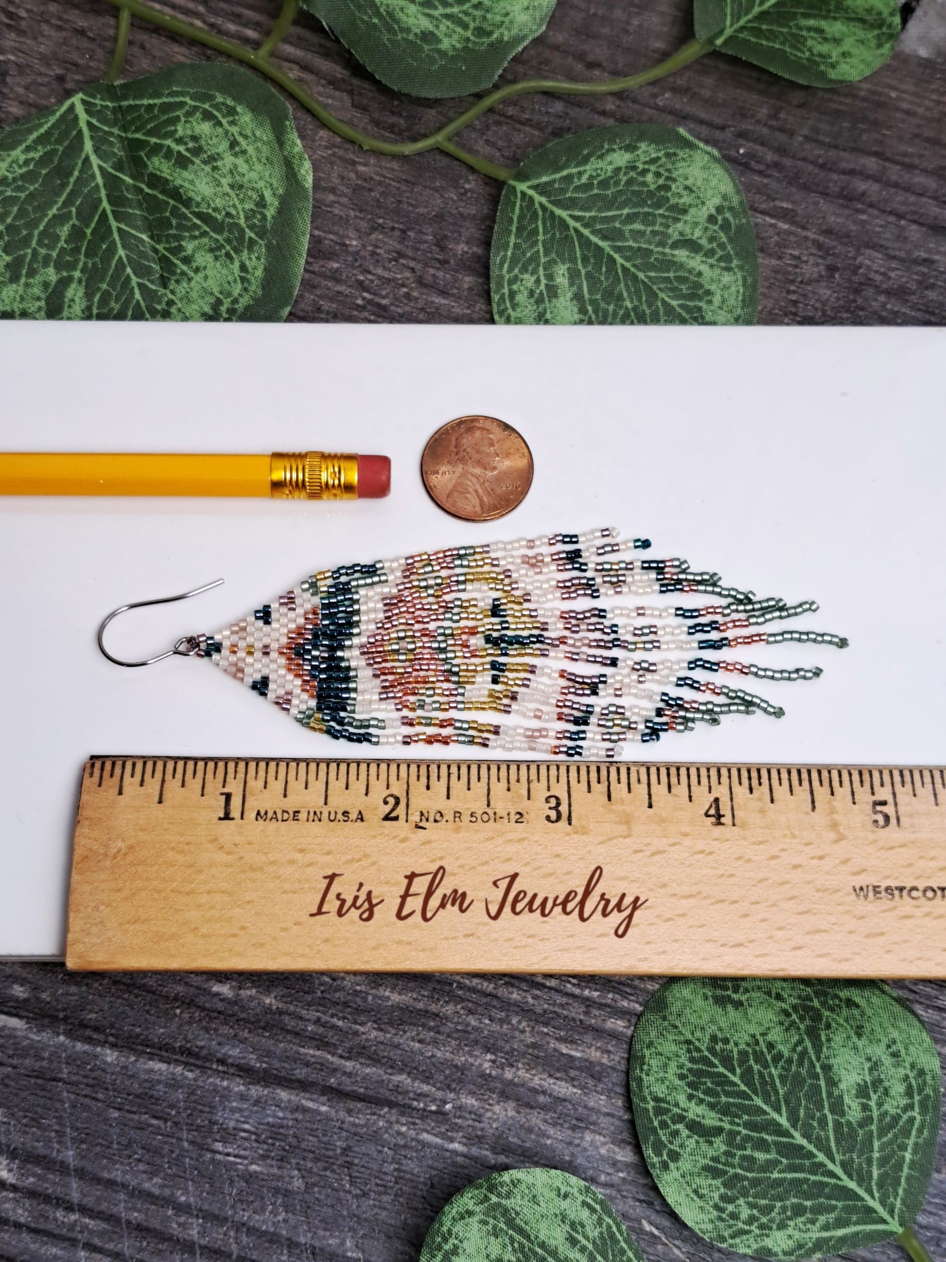 4.75 inch long fringe earring on a wooden ruler with leaves in the background