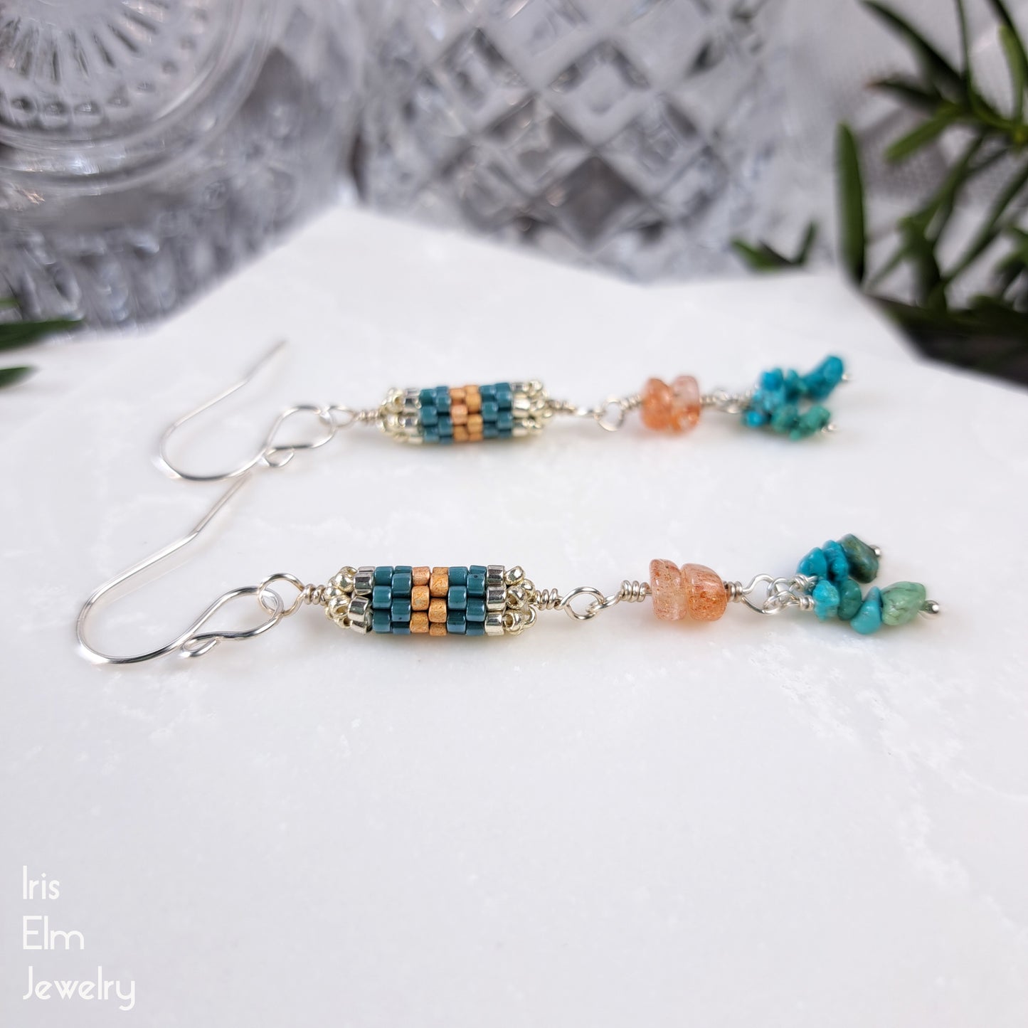 Beaded earrings with turquoise gemstone and peach sunstone beads on a white surface.