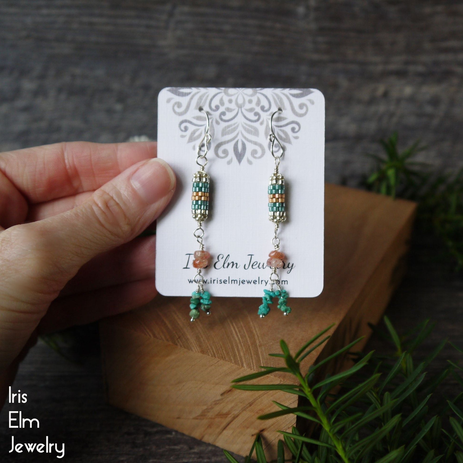 Pair of beaded turquoise and sunstone earrings with seed bead beadwork on a 'Iris Elm Jewelry' card held by a hand with a natural background.