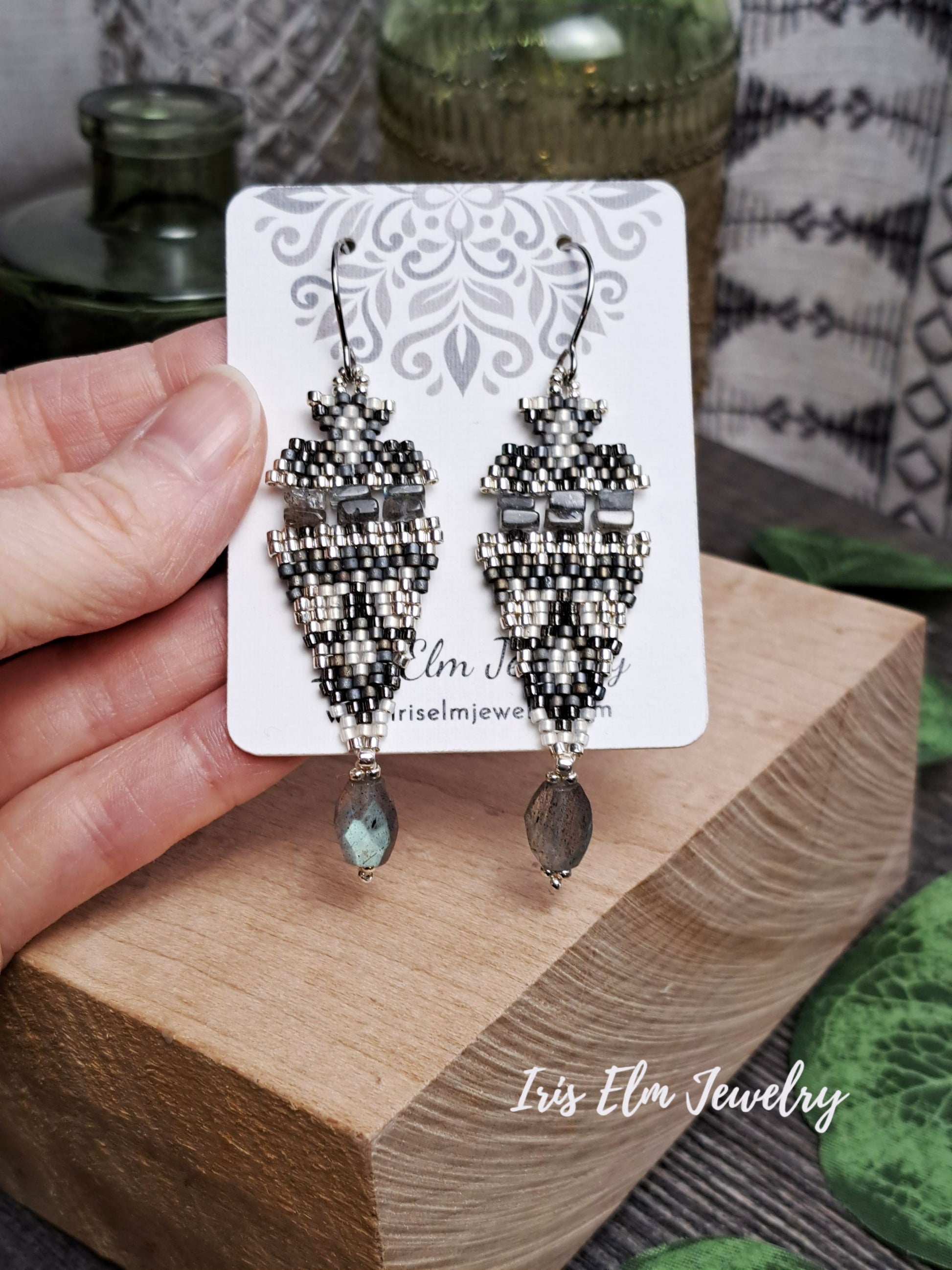 iridescent labradorite stone and seed bead boho beadwork beaded earrings on a card with 'Iris Elm Jewelry' branding, held by a hand.