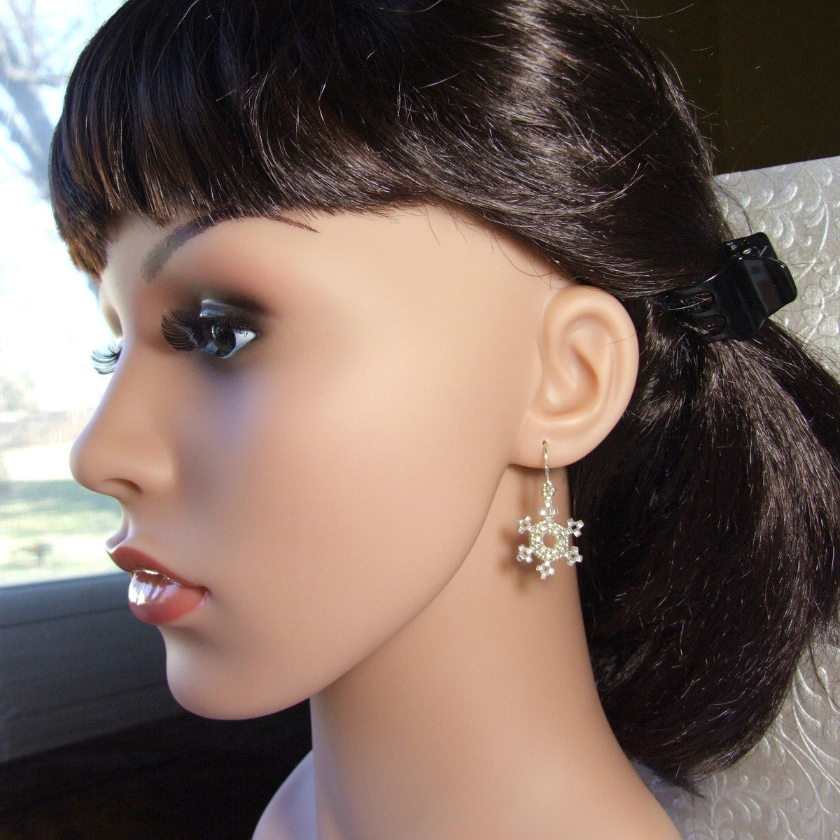 Mannequin head with dark hair and a snowflake earring.