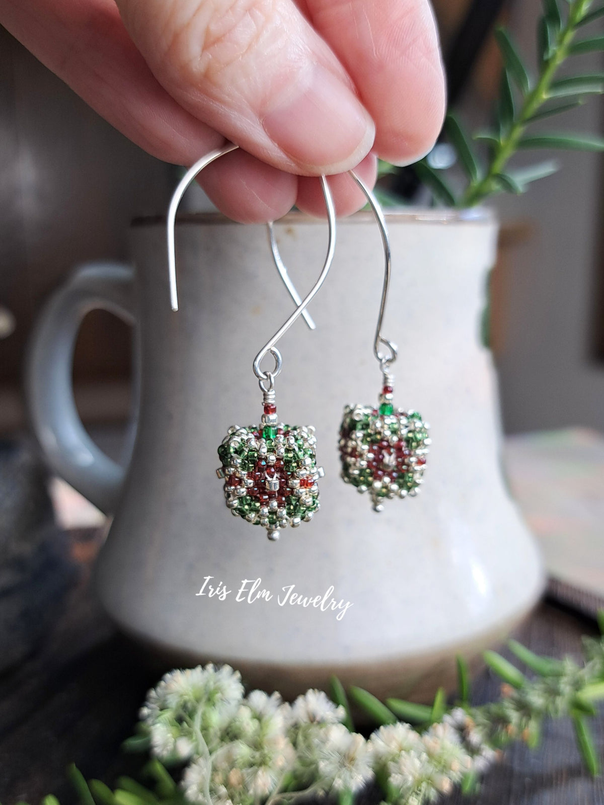 red, green, and silver seed bead cube shaped drop earrings held by hand