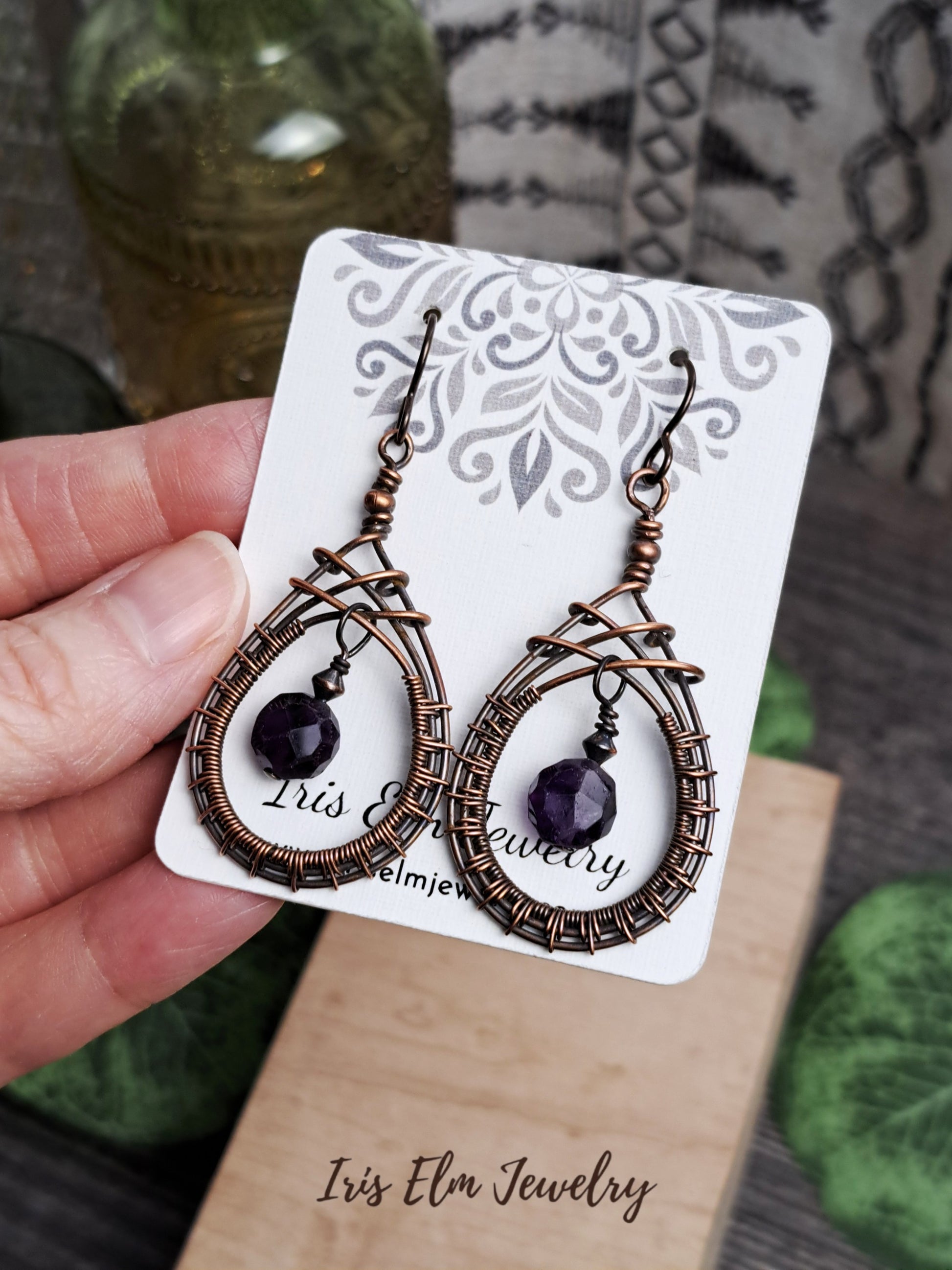 Pair of copper wire woven teardrop amethyst earrings on a 'Iris Elm Jewelry' card.
