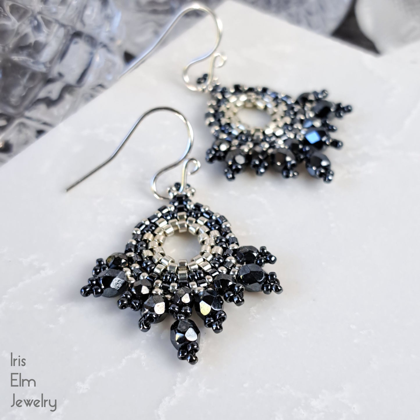pewter grey and silver beaded glass artisan earrings on a textured white surface with 'Iris Elm Jewelry' branding.