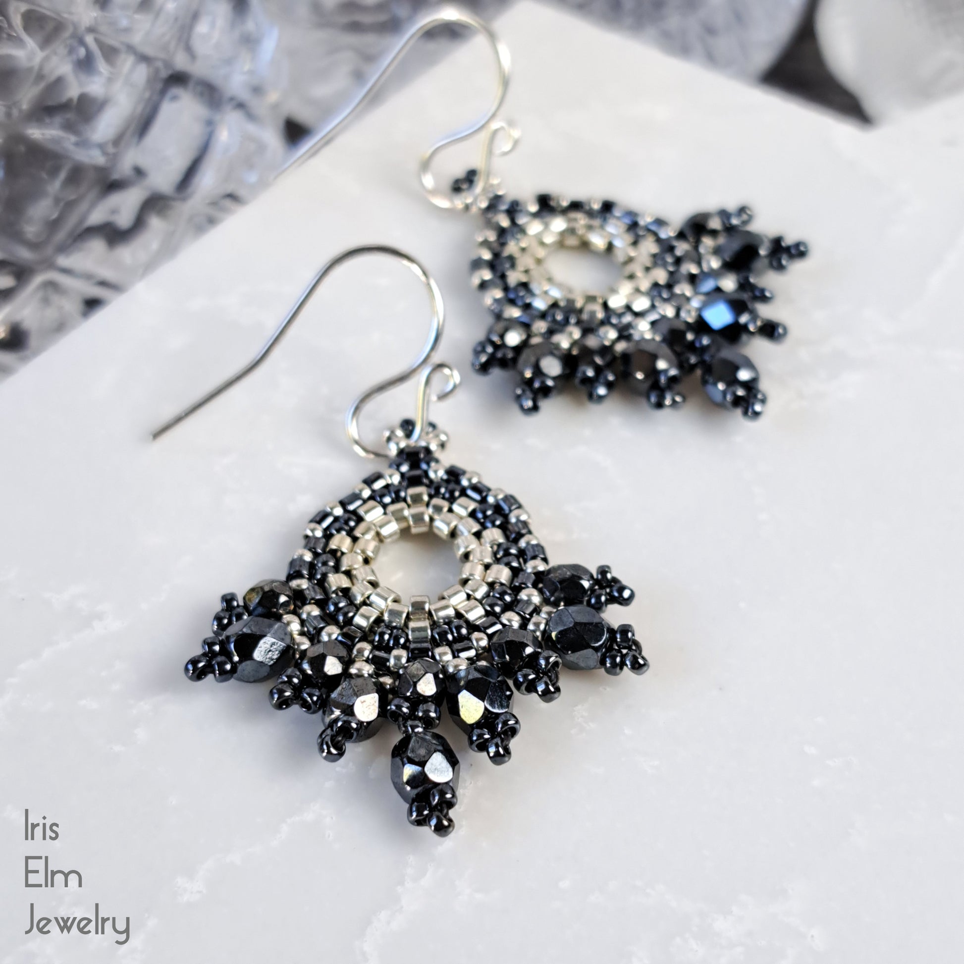 pewter grey and silver beaded glass artisan earrings on a textured white surface with 'Iris Elm Jewelry' branding.