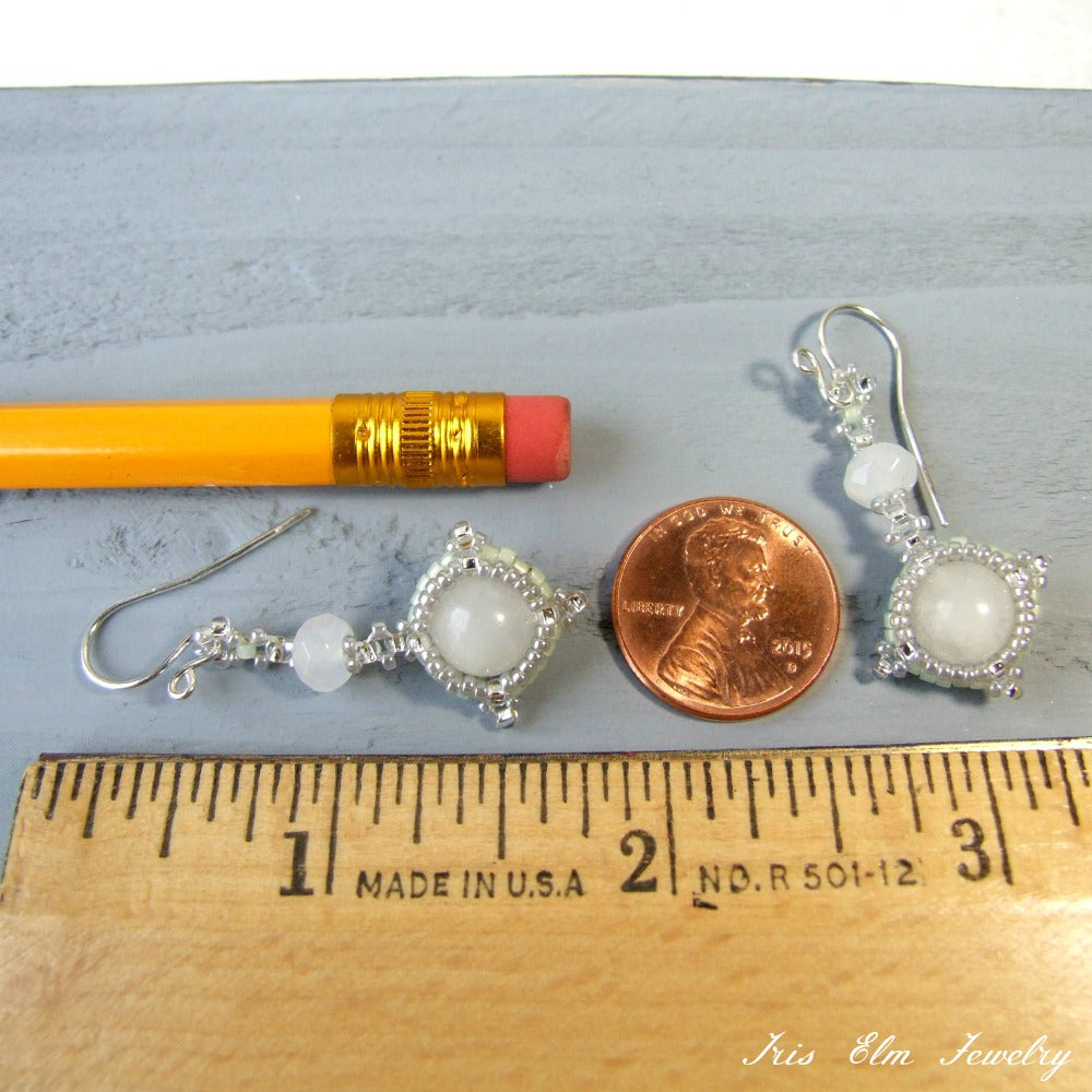 Pair of beaded white quartz earrings with a pencil and penny for scale on a wooden ruler.