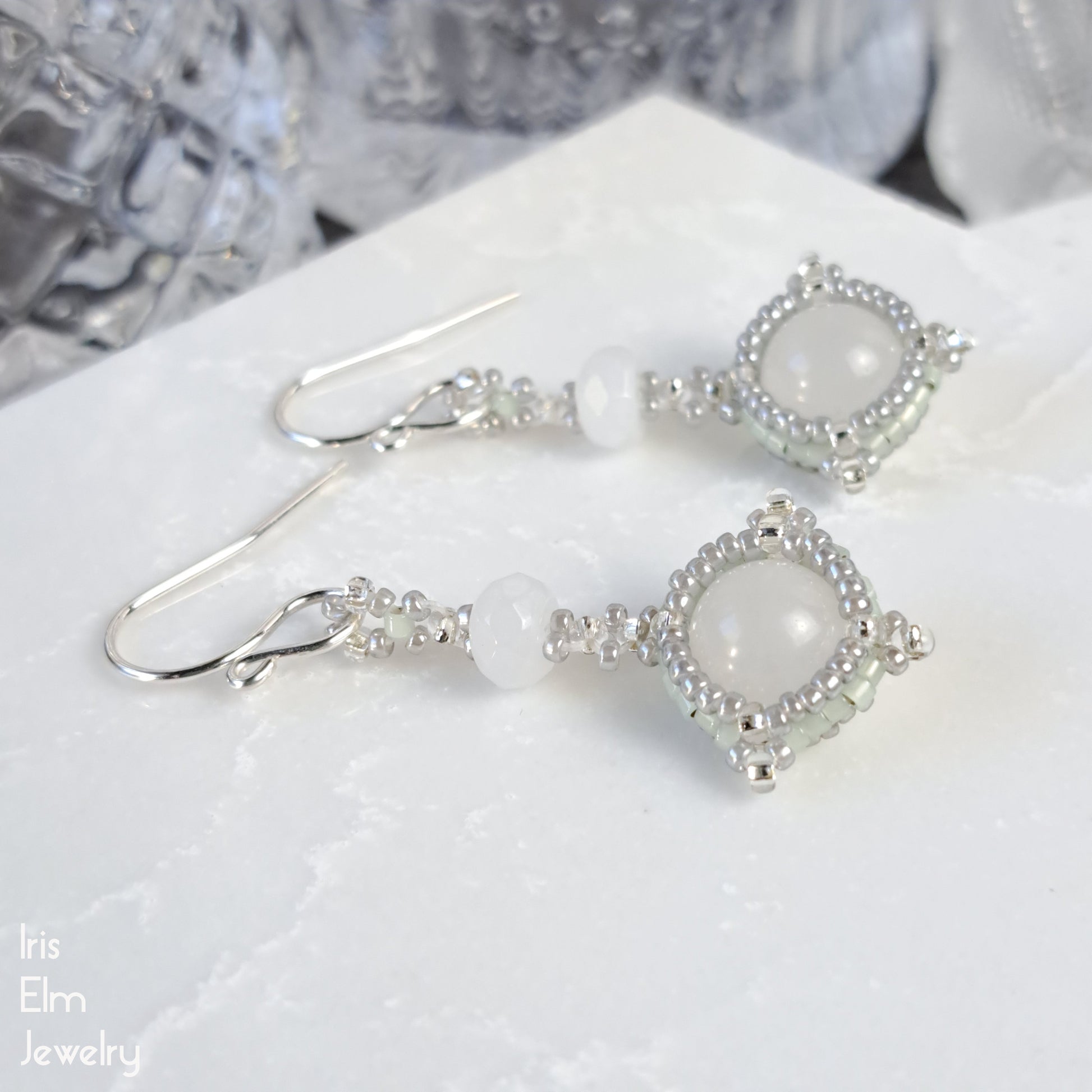 Quartz drop handmade earrings with seed bead accents on a white surface, branded 'Iris Elm Jewelry'.