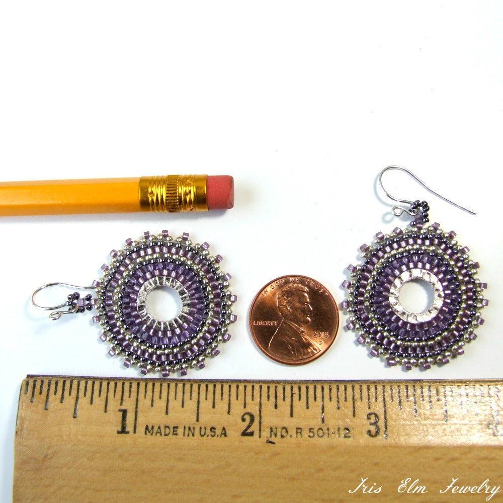 Pair of purple beaded earrings next to a penny and ruler for size comparison on a white background.