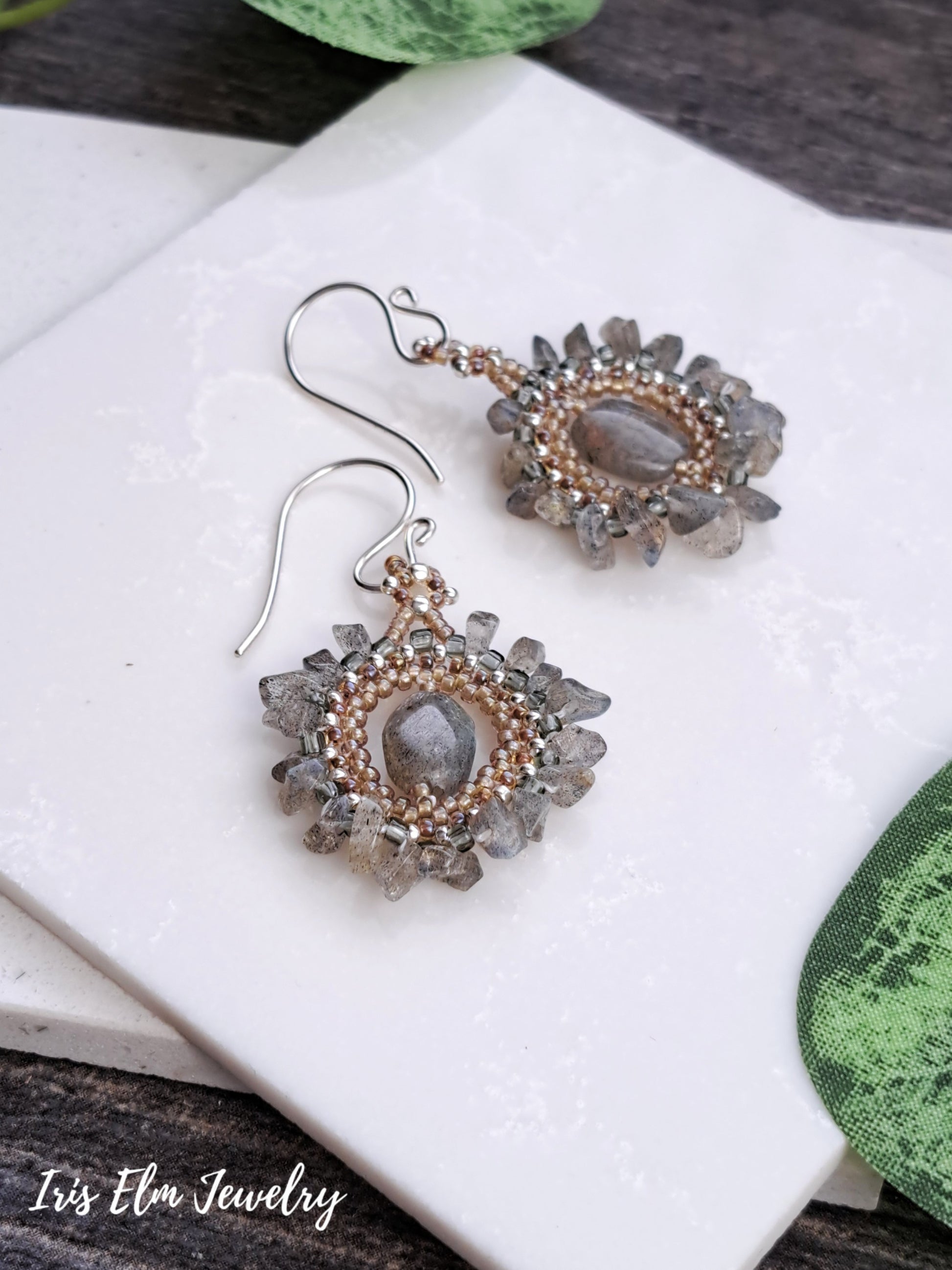 Pair of bohemian labradorite beadwork handmade earrings with gemstone centers on a white surface.