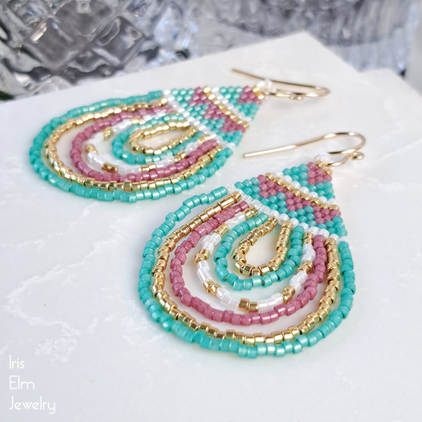 beadwork pink, mint, and gold seed bead teardrop geometric earrings on a white surface with 'Iris Elm Jewelry' branding.