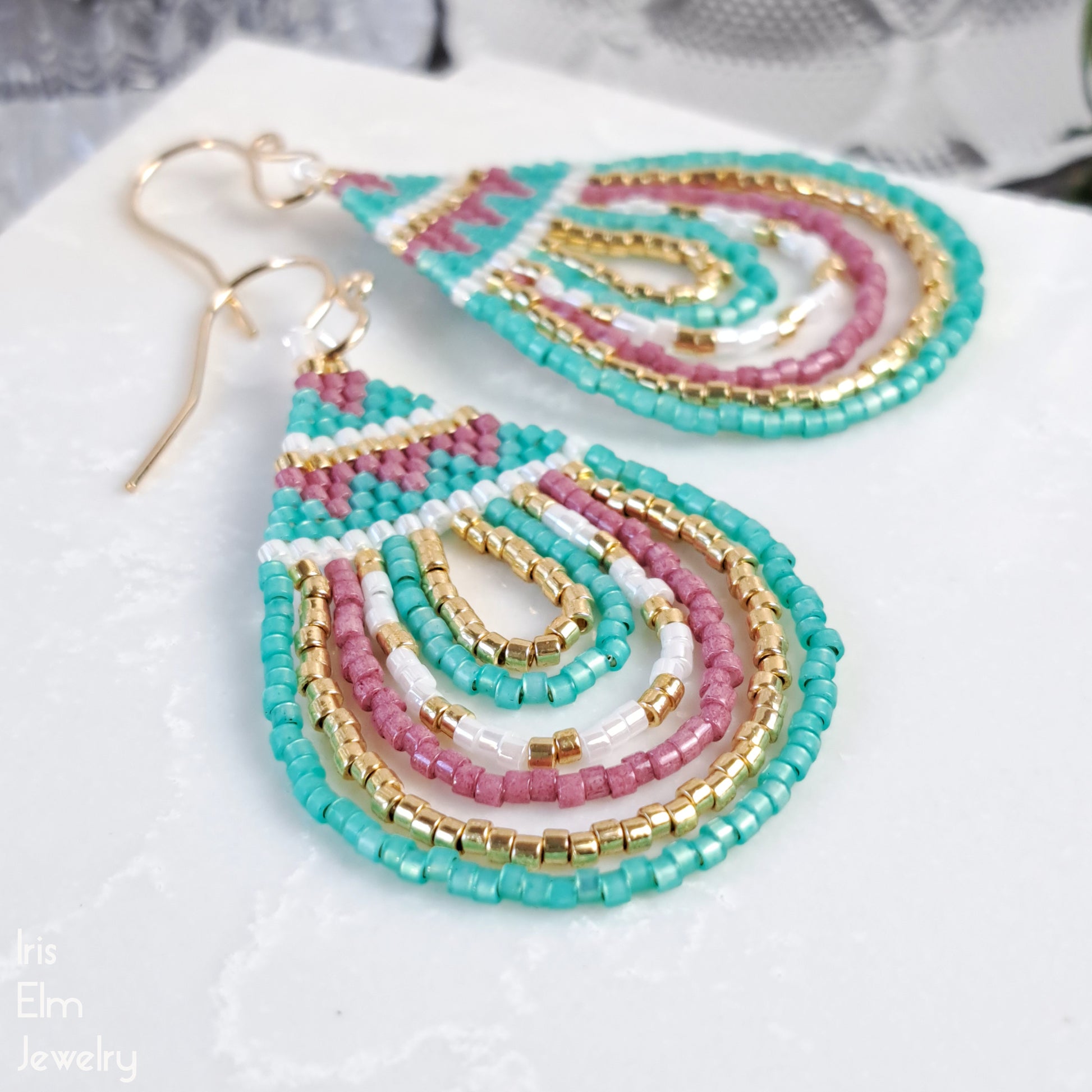 Colorful beaded earrings on a white surface with 'Iris Elm Jewelry' branding.