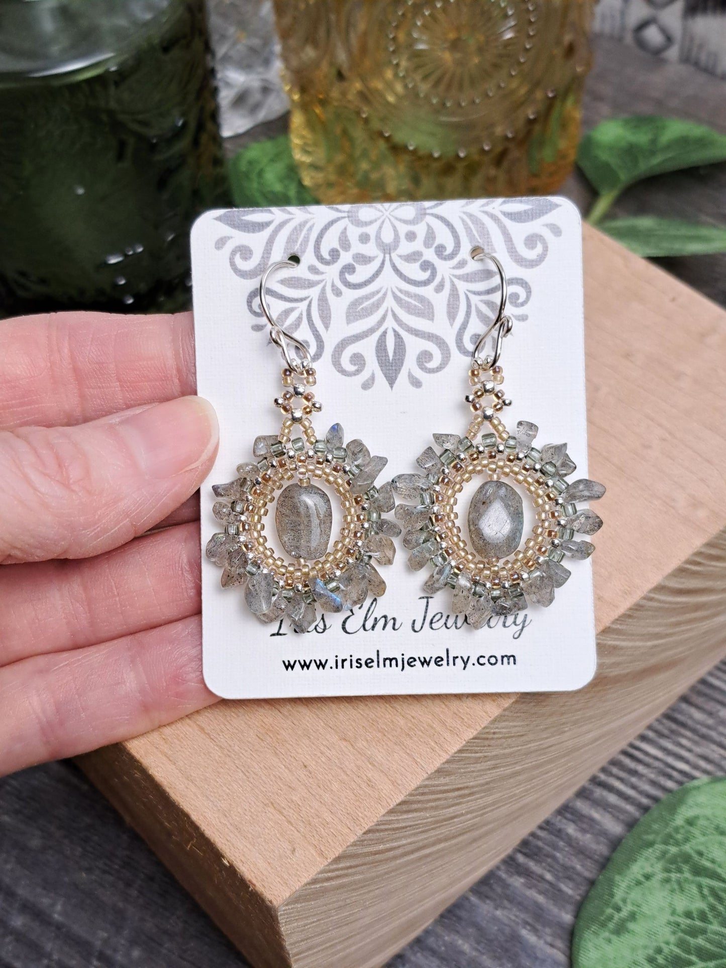 Decorative bohemian labradorite beadwork handmade earrings on a card held by a hand with a blurred background