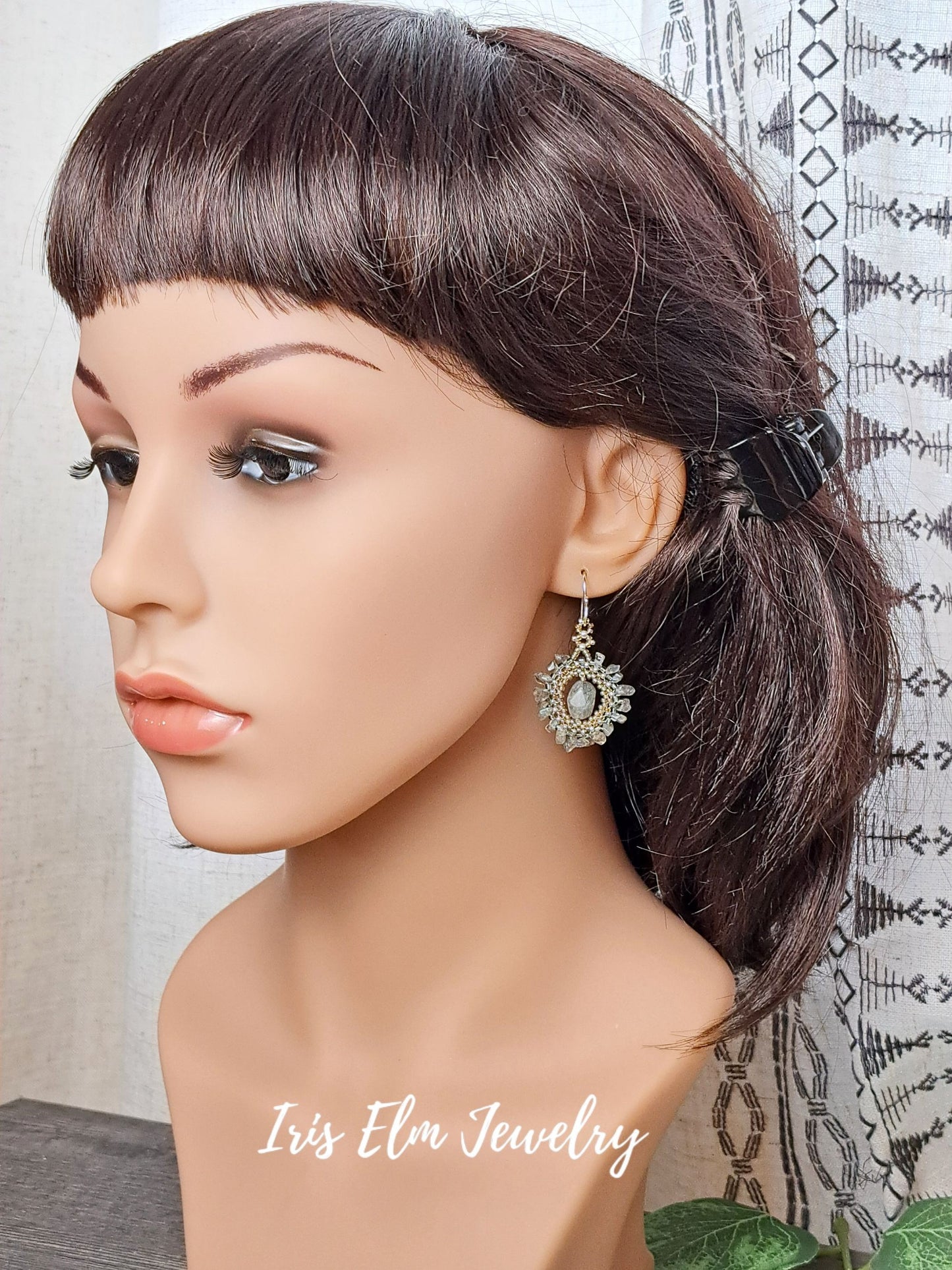 Mannequin head with brown hair styled in a ponytail, wearing earrings with 'Iris Elm Jewelry' branding.